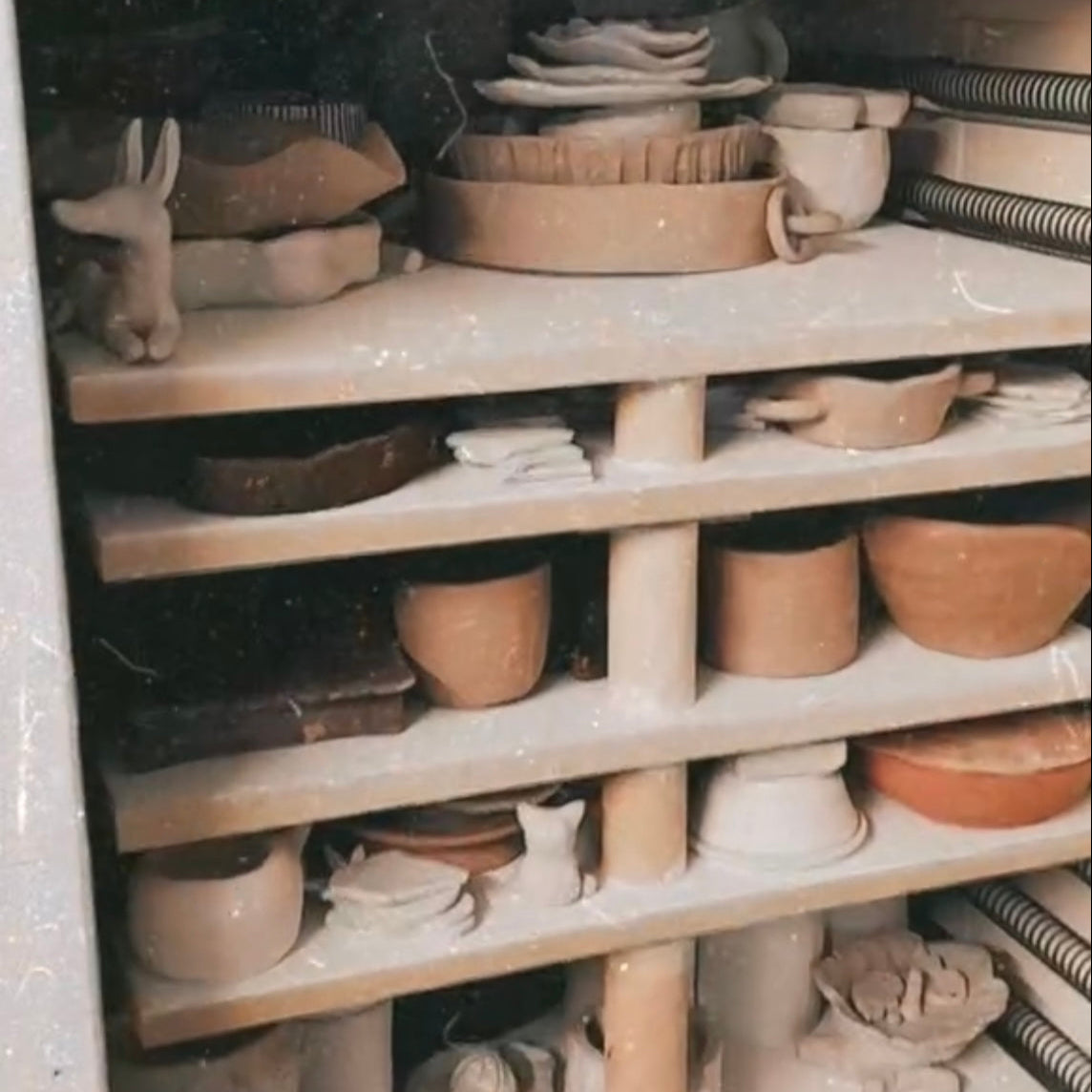 Kiln shelves filled with various clay pots and bowls waiting to be fired