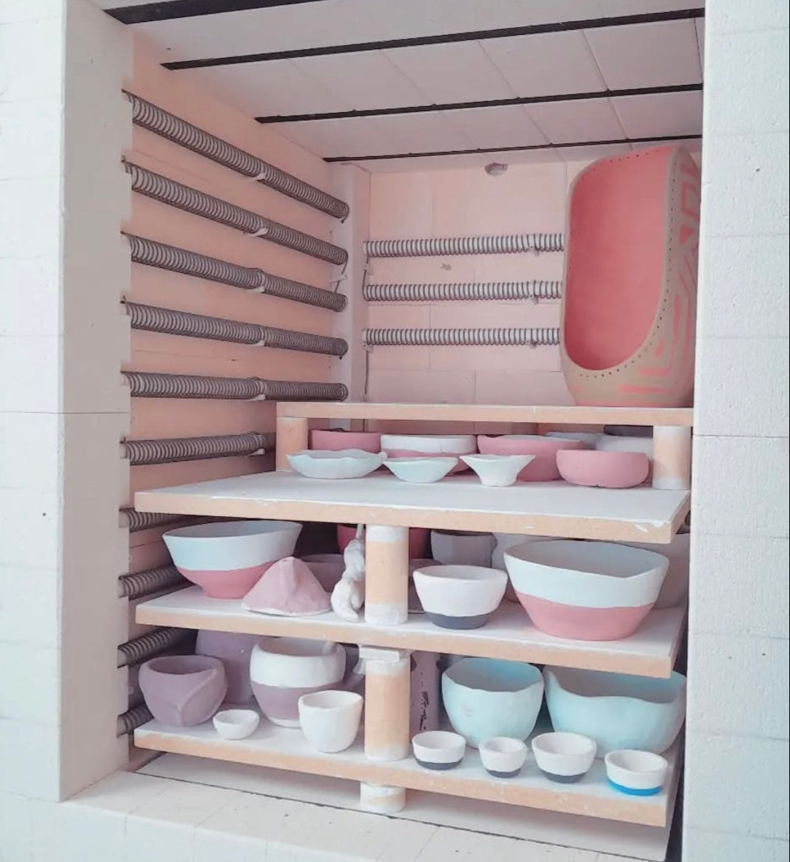 A kiln half filled with assorted shaped pots waiting to be glaze fired