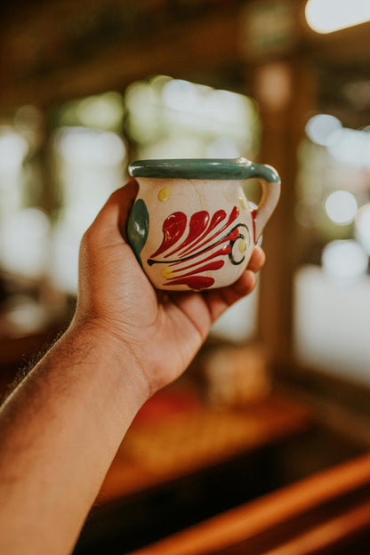Hand holding up a ceramic mug with an abstract design