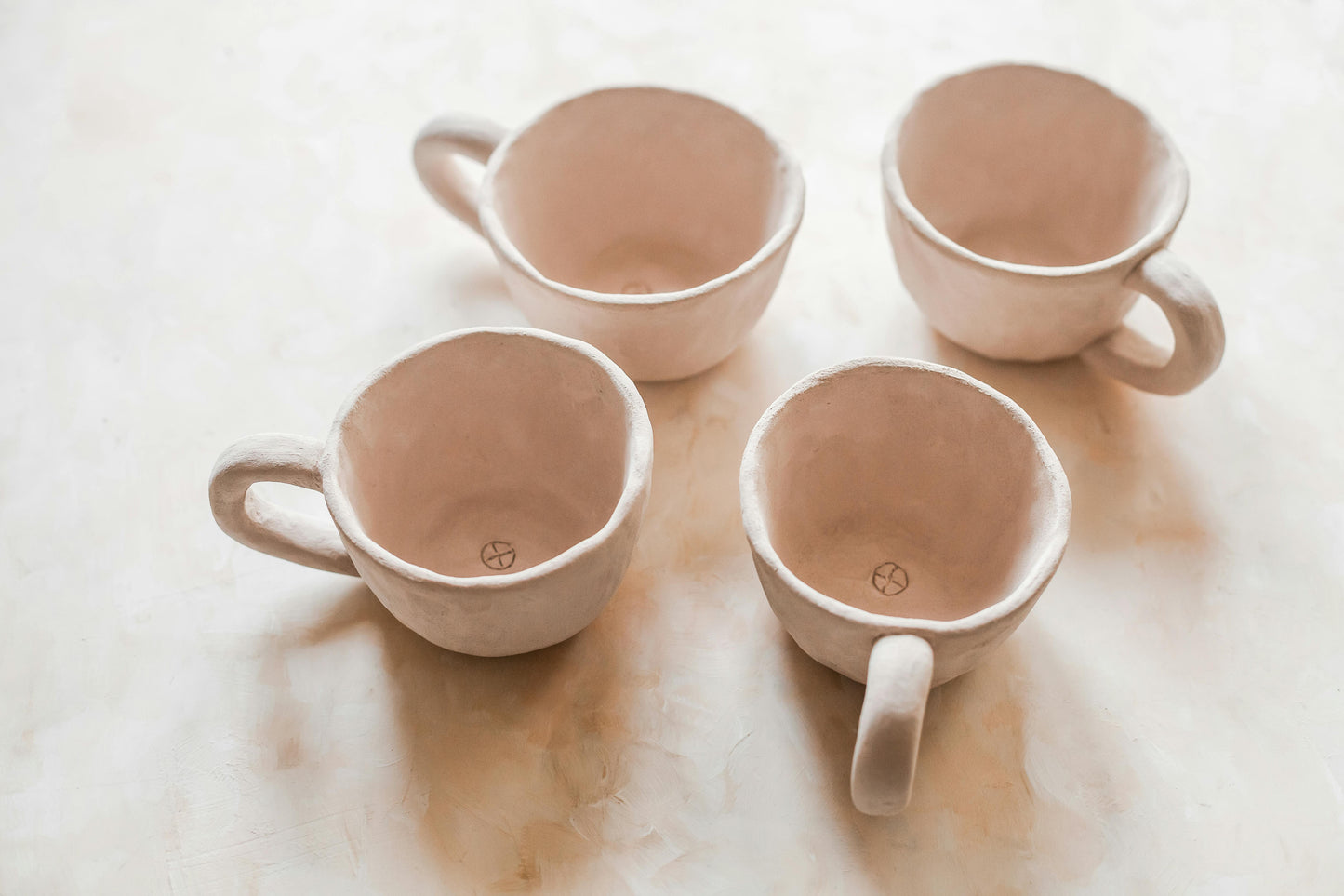 Four hand made ceramic cups/mugs on a light surface